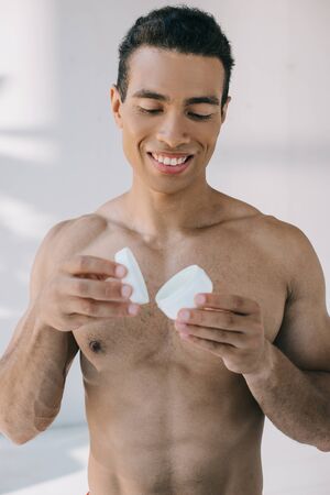 handsome mixed race man opening container with cosmetic creamの写真素材