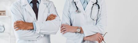 panoramic shot of doctors standing with crossed arms in clinic の写真素材