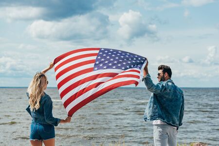 blonde woman and man in jacket holding american flag