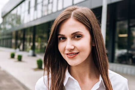 attractive young woman in white shirt smiling on streetの写真素材