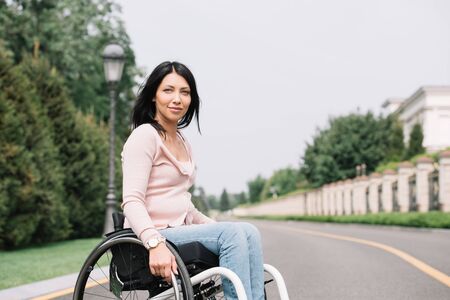 young disabled woman in wheelchair smiling and looking at cameraの写真素材