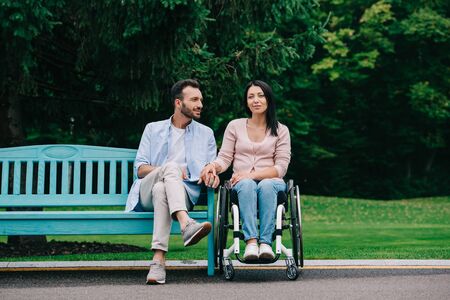 handsome man with happy disabled woman resting in park togetherの写真素材