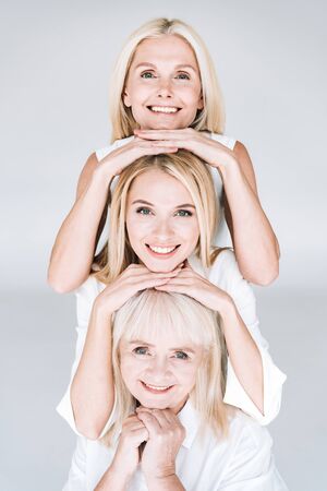 beautiful smiling three generation blonde women isolated on greyの写真素材