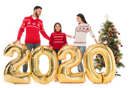 happy family in sweaters standing near balloons and christmas tree isolated on whiteの写真素材