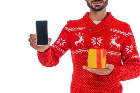 cropped view of bearded man holding smartphone with blank screen and gift isolated on whiteの写真素材