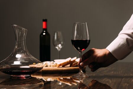 cropped view of man holding wine glass at table in restaurantの写真素材