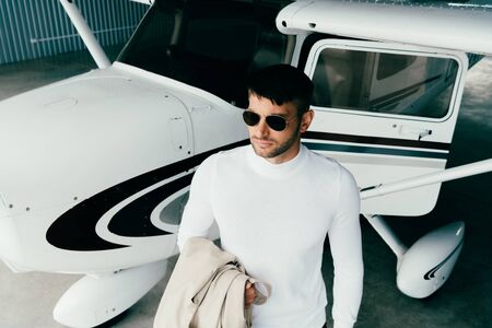 high angle view of man in sunglasses and casual attire standing near plane and looking away