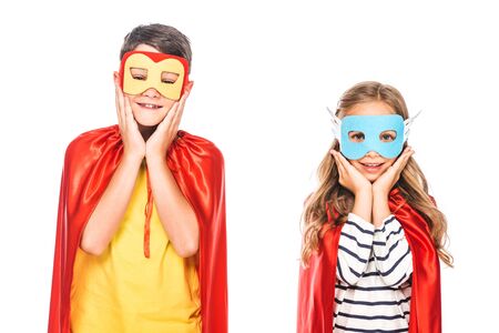 front view of two smiling kids in masks and hero cloaks isolated on whiteの写真素材