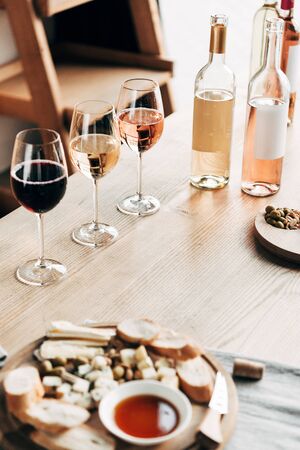 wine glasses, bottles of wine and food on wooden table