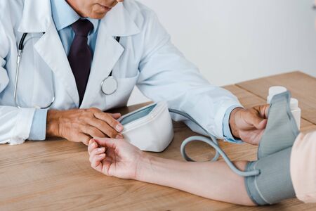 cropped view of doctor measuring blood pressure of patient in clinic の写真素材