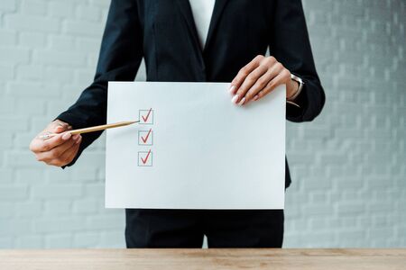 cropped view of woman holding pencil near paper with check list の写真素材
