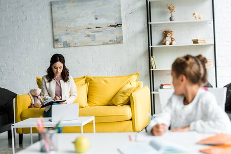 selective focus of attractive woman writing while sitting on sofaの写真素材