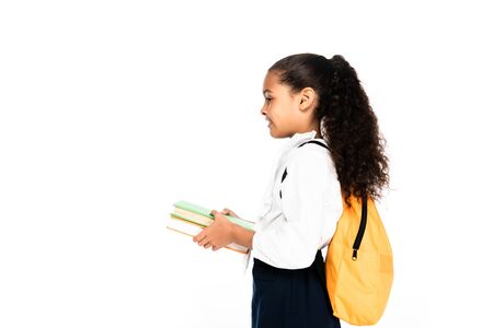 side view of african american schoolgirl with backpack holding books isolated on whiteの写真素材