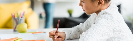 panoramic shot of cute kid drawing with color pencil 
