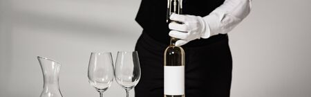 panoramic shot of waiter in white glove opening bottle of wine in restaurantの写真素材