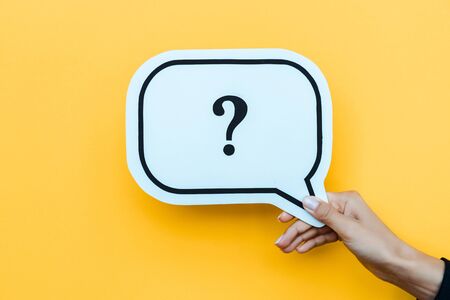 cropped view of woman holding speech bubble with question mark on orange の写真素材