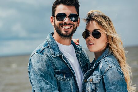 attractive woman and handsome man in denim jackets looking at camera