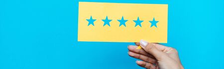 panoramic shot of woman holding yellow paper with stars isolated on blue 