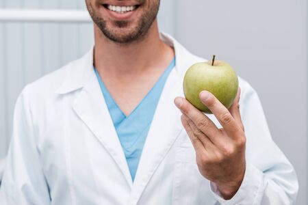 cropped view of happy bearded man holding green and tasty appleの写真素材
