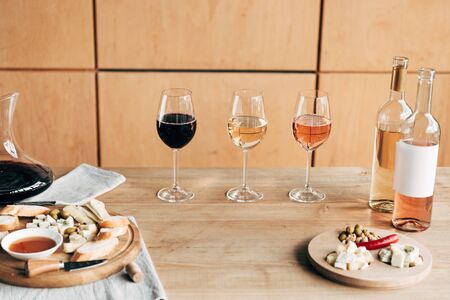 wine glasses, bottles of wine and food on wooden tableの写真素材