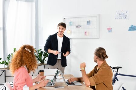 back view of friends looking at smiling man in shirt