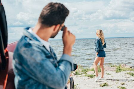 selective focus of blonde woman in denim shorts and jacket looking awayの写真素材