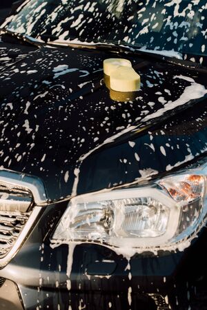 yellow sponge on wet and luxury black car in foamの写真素材