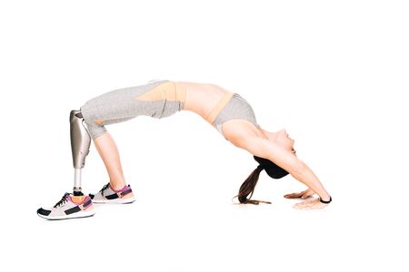 side view of disabled sportswoman with prosthesis doing bridge exercise isolated on white