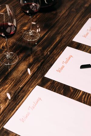 wine tasting documents, pen and wine glasses on wooden tableの写真素材