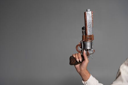 cropped view of woman holding vintage pistol isolated on grey