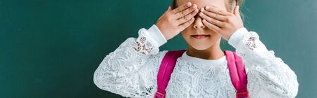 panoramic shot of cute kid covering eyes with hands on green 
