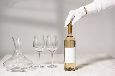 partial view of waiter holding bottle of wine in restaurant