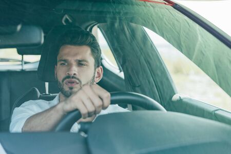 handsome man in white shirt driving car and looking awayの写真素材
