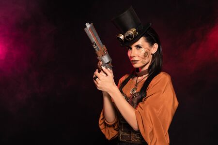 beautiful steampunk woman in top hat holding pistol in pink smokeの写真素材