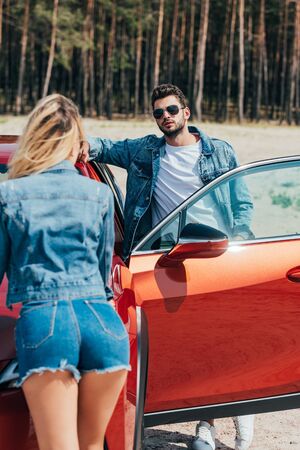woman and handsome man in jacket standing near car