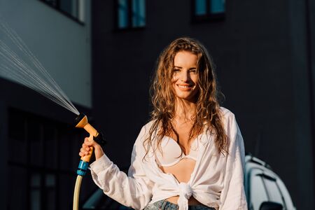 happy woman holding pressure washer and looking at camera