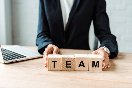 selective focus of businesswoman touching wooden cubes with team lettersの写真素材