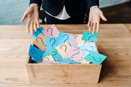 cropped view of woman gesturing near box with question marks on sticky notes の写真素材
