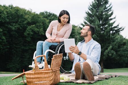 cheerful disabled woman and smiling boyfriend using digital tablet in parkの写真素材