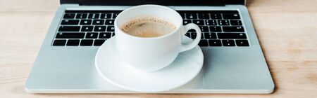 panoramic shot of cup of coffee on laptop in officeの写真素材