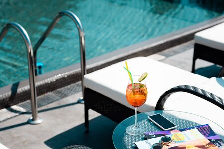 table with cocktail, magazines and sunglasses near swimming pool on resortの写真素材