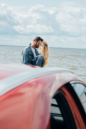 selective focus of woman and man in denim jackets kissing outside の写真素材