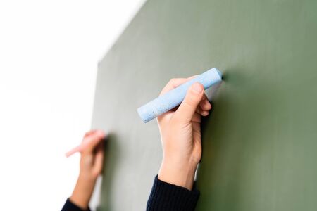 parftial view of two multicultural schoolgirls writing on chalkboard isolated on whiteの写真素材