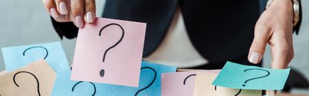 panoramic shot of woman holding pink sticky note with question mark 