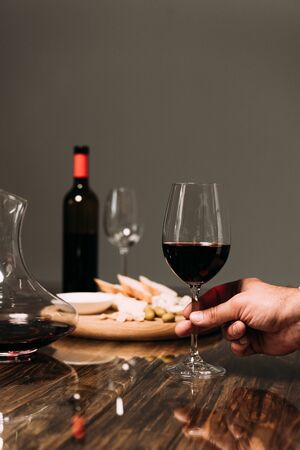 cropped view of man holding wine glass at table in restaurantの写真素材