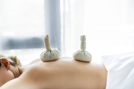 woman lying on massage mat with herbal balls on back の写真素材