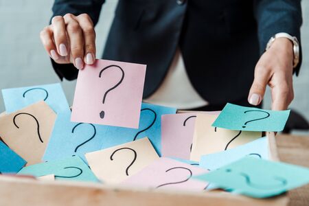cropped view of woman holding pink sticky note with question mark の写真素材