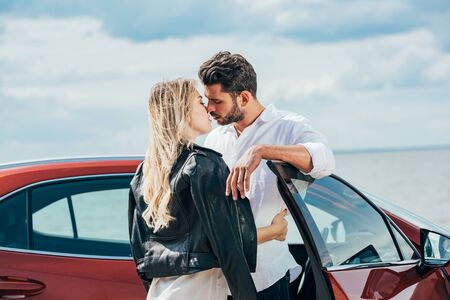 attractive woman and handsome man kissing and hugging near carの写真素材