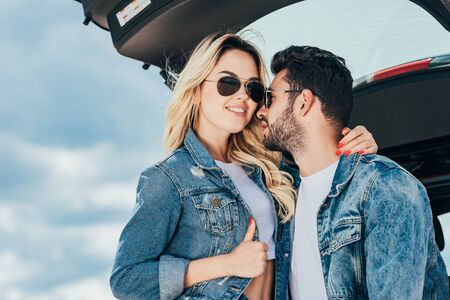 attractive woman and handsome man in denim jackets hugging outside
