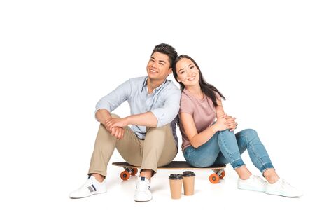 chappy asian couple sitting on longboard and smiling at camera on white backgroundの写真素材